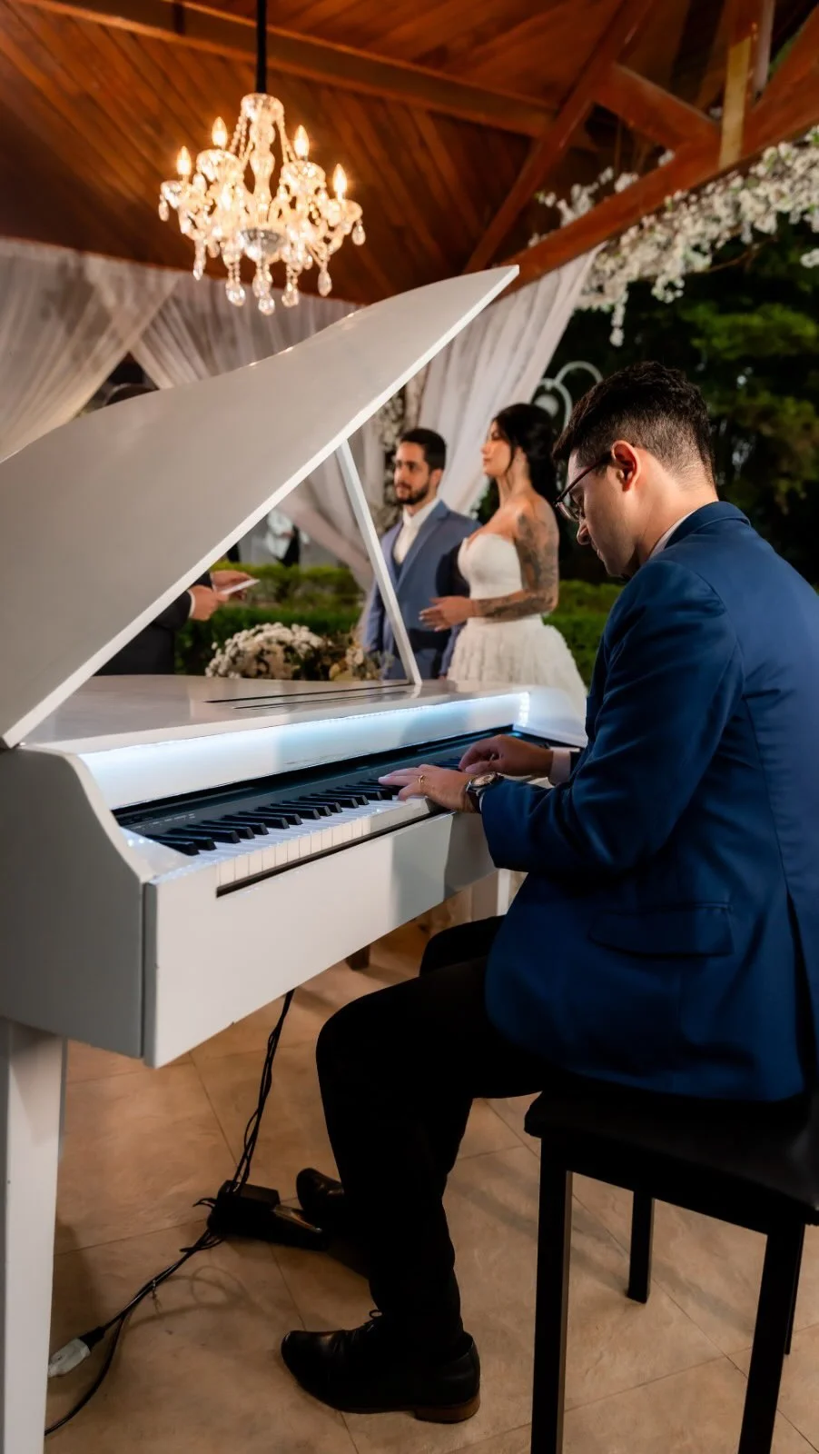Pianista em piano de cauda branco na cerimônia de casamento